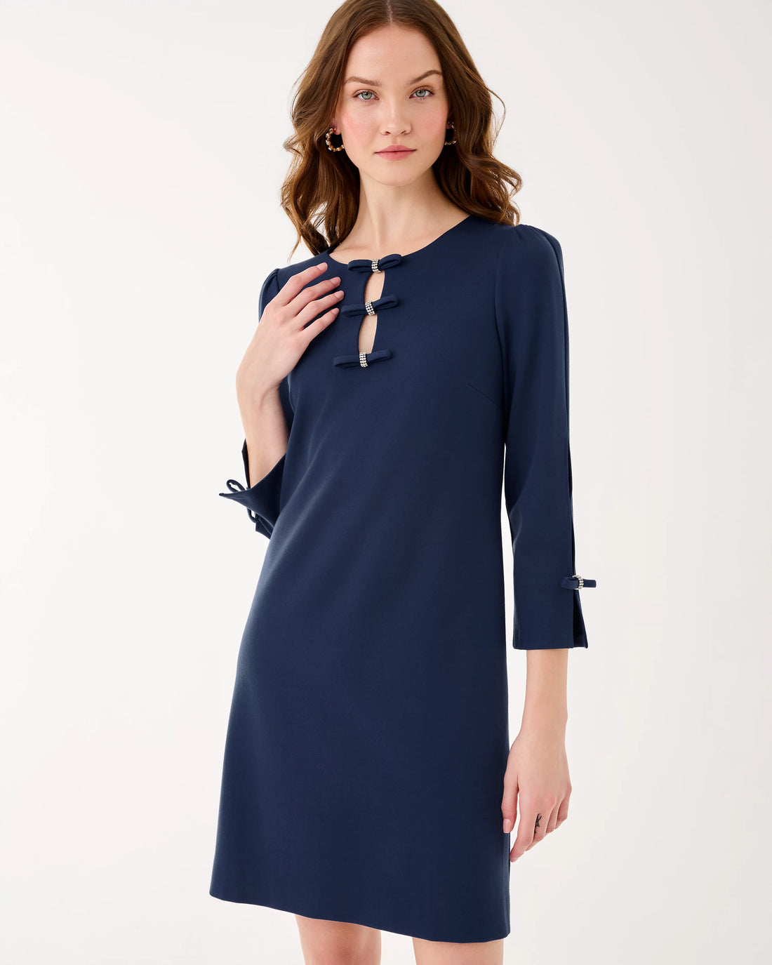 Woman wearing a navy blue dress with ruffled details on a white background