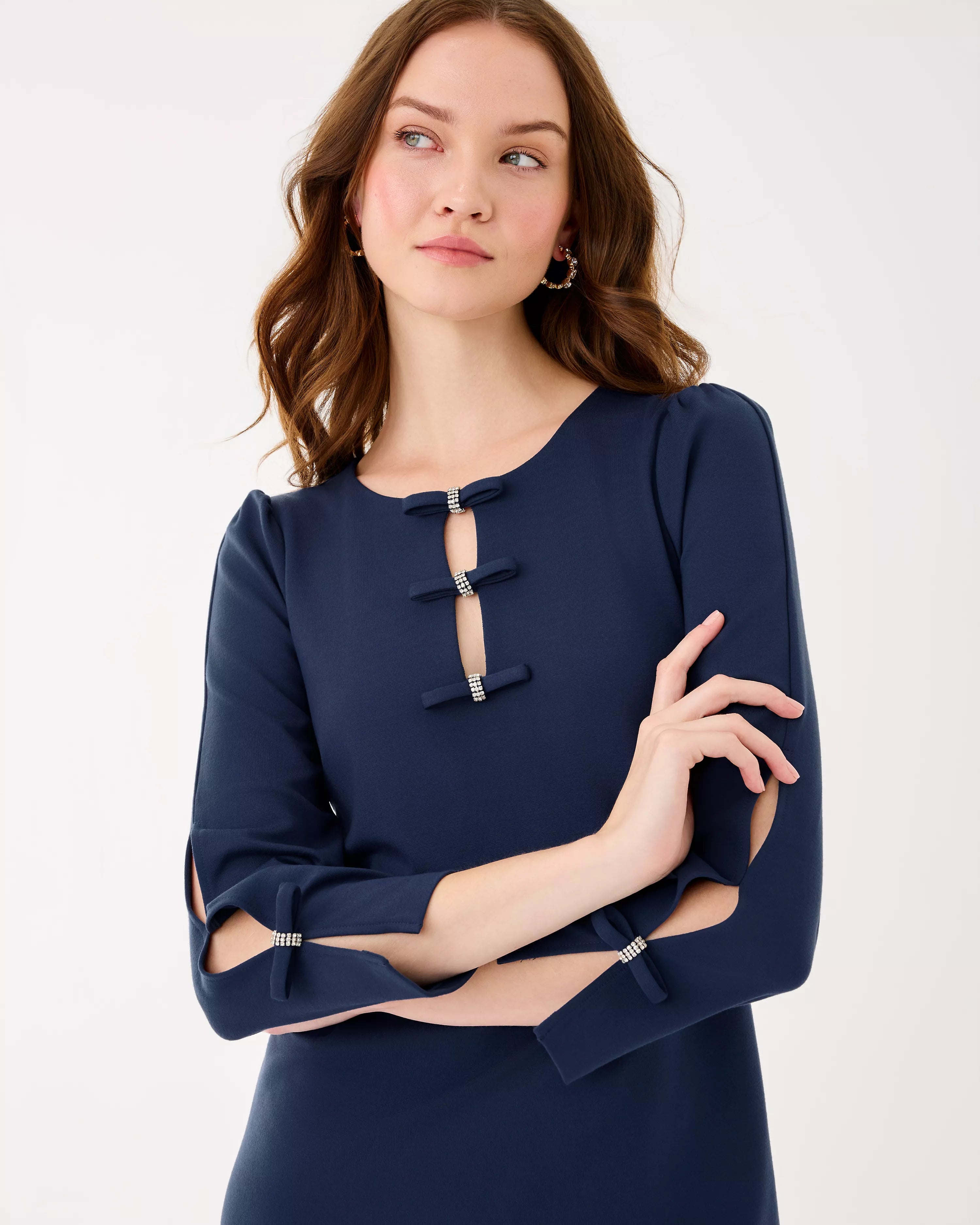Woman wearing a navy blue dress with cut-out sleeves on a white background