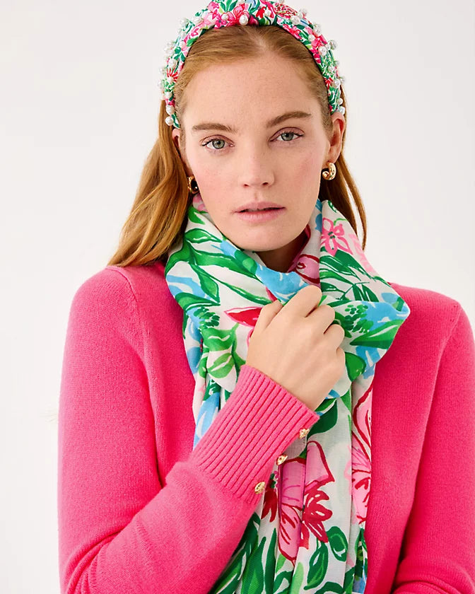 Woman wearing a colorful floral headband and scarf against a white background