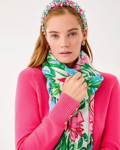 Woman wearing a colorful floral headband and scarf against a white background
