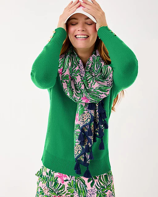 Woman wearing a green sweater and colorful scarf with a white background
