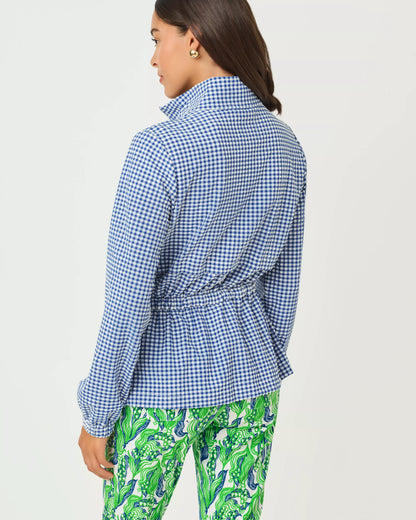 Woman wearing a blue checkered shirt and green patterned pants on a white background