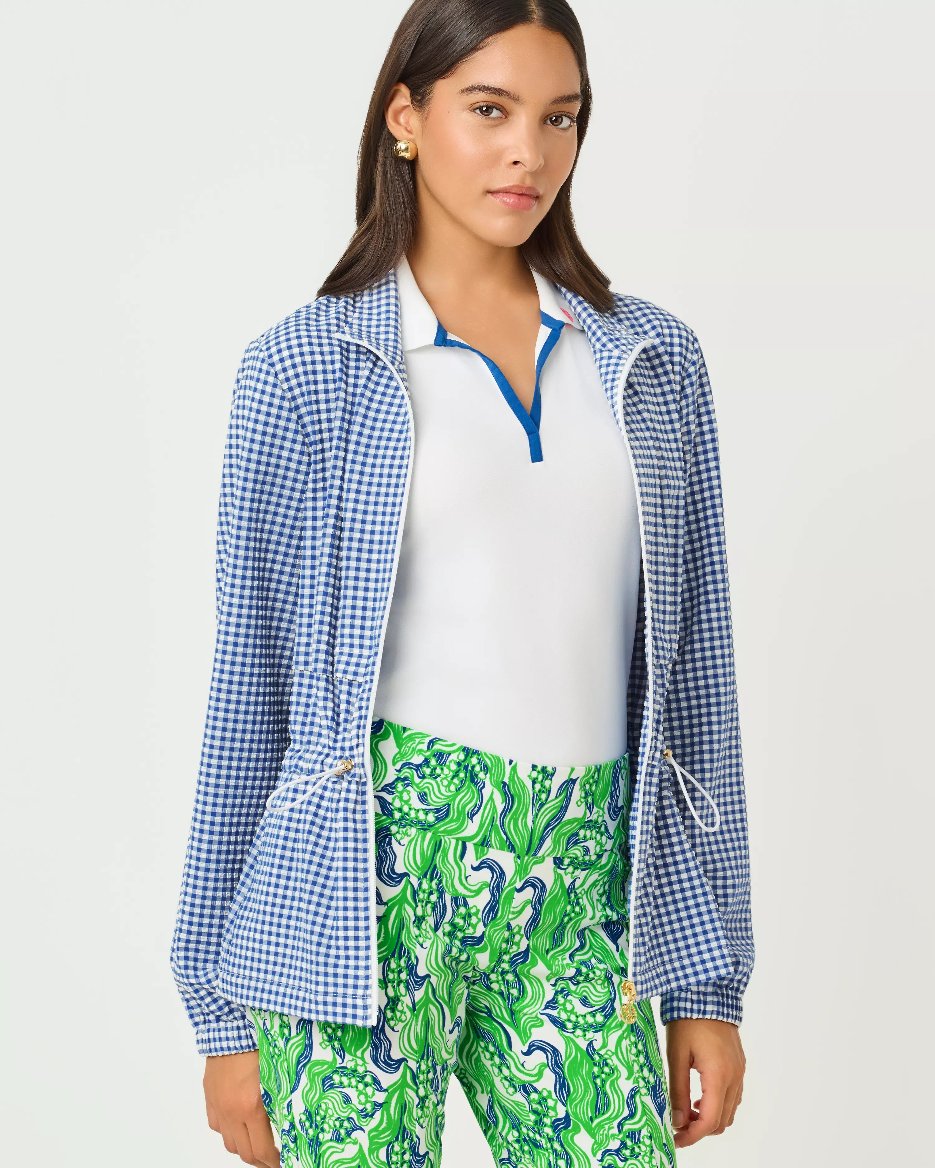 Woman wearing a blue checkered jacket, white shirt, and green patterned pants on a light gray background