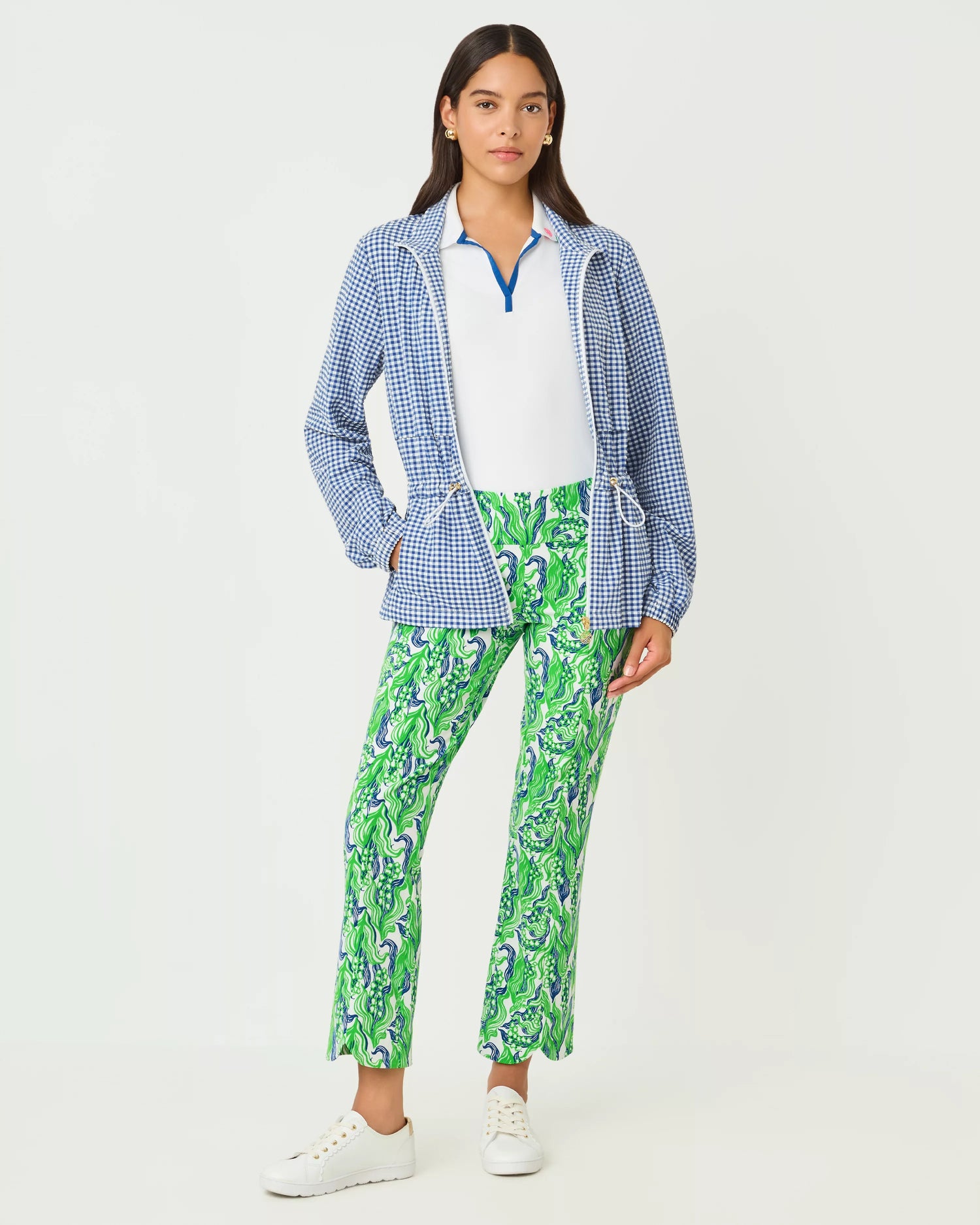 Woman wearing a blue checkered jacket, white shirt, and green patterned pants on a white background