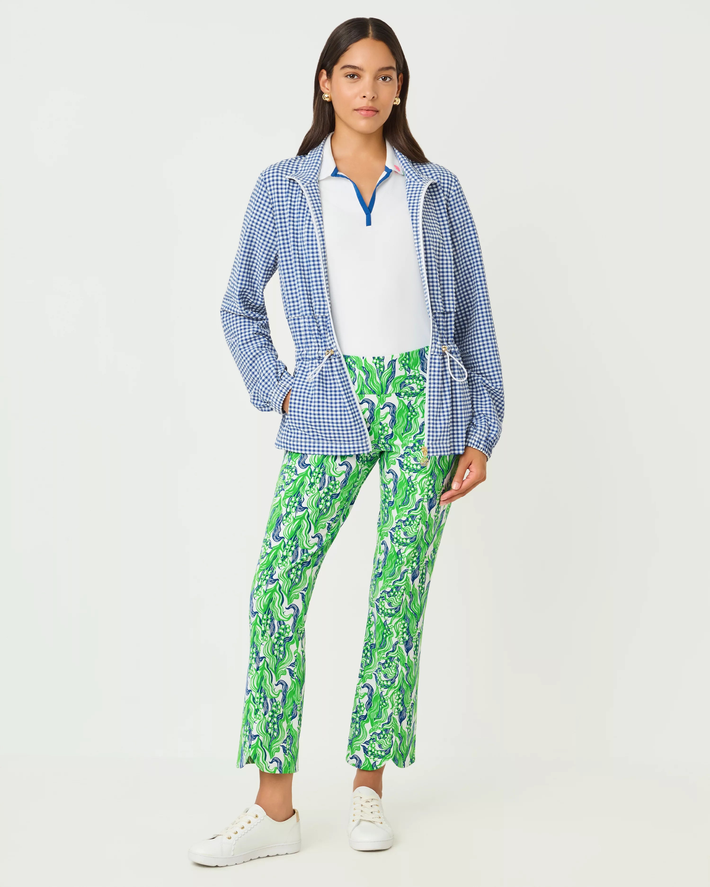 Woman wearing a blue checkered jacket, white shirt, and green patterned pants on a white background