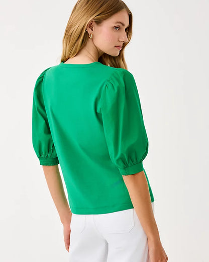 Woman wearing a green blouse with puffed sleeves on a white background