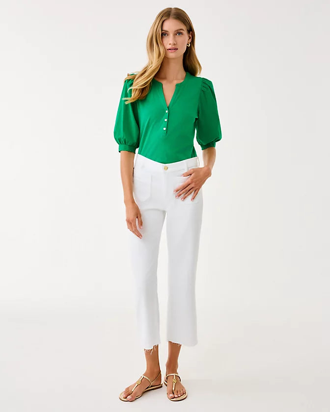 Woman wearing a green blouse and white pants on a white background