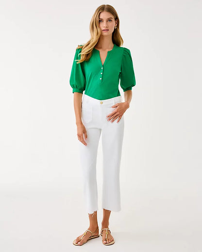 Woman wearing a green blouse and white pants on a white background