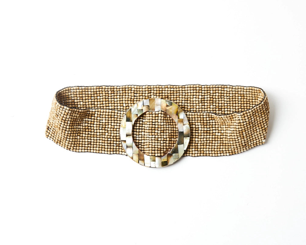 A wide beaded belt with a textured pattern of small gold and white beads, featuring a large central circular buckle made of polished mother-of-pearl tiles by Mare Sole Amore Beige Oz Slip On Stretch Belt 