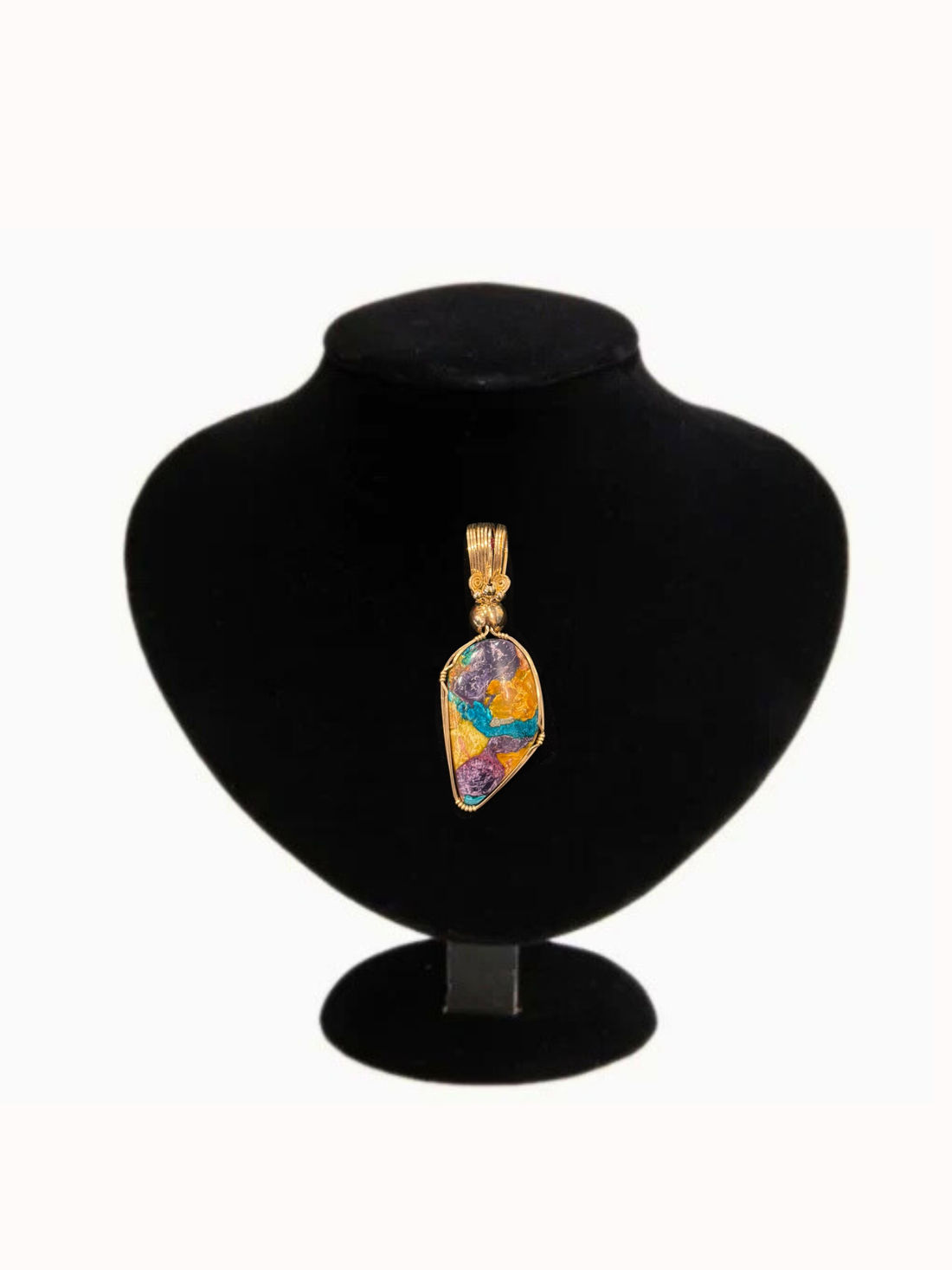Multicolored pendant on a black velvet stand with a white background