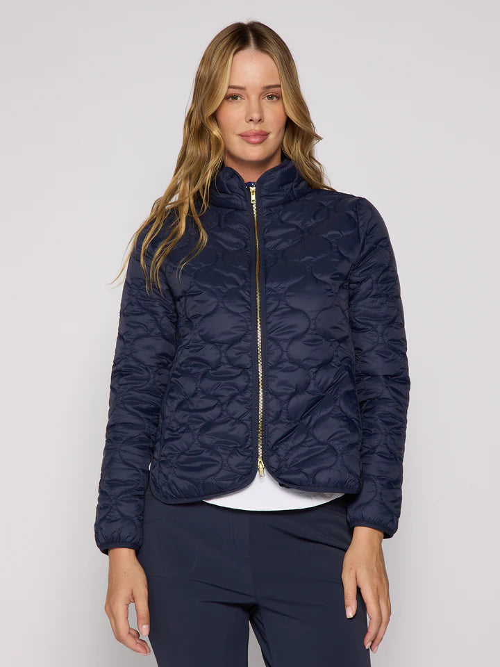 Woman wearing a navy quilted jacket on a plain background