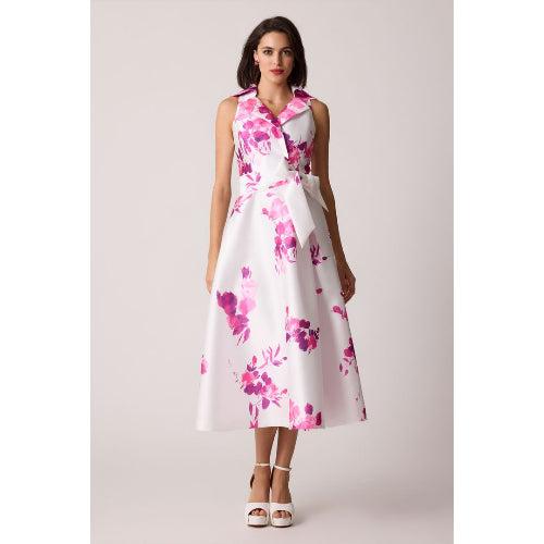 Woman wearing a white dress with pink floral pattern on a plain background