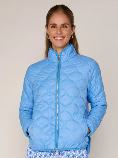Woman wearing a blue quilted jacket against a plain background