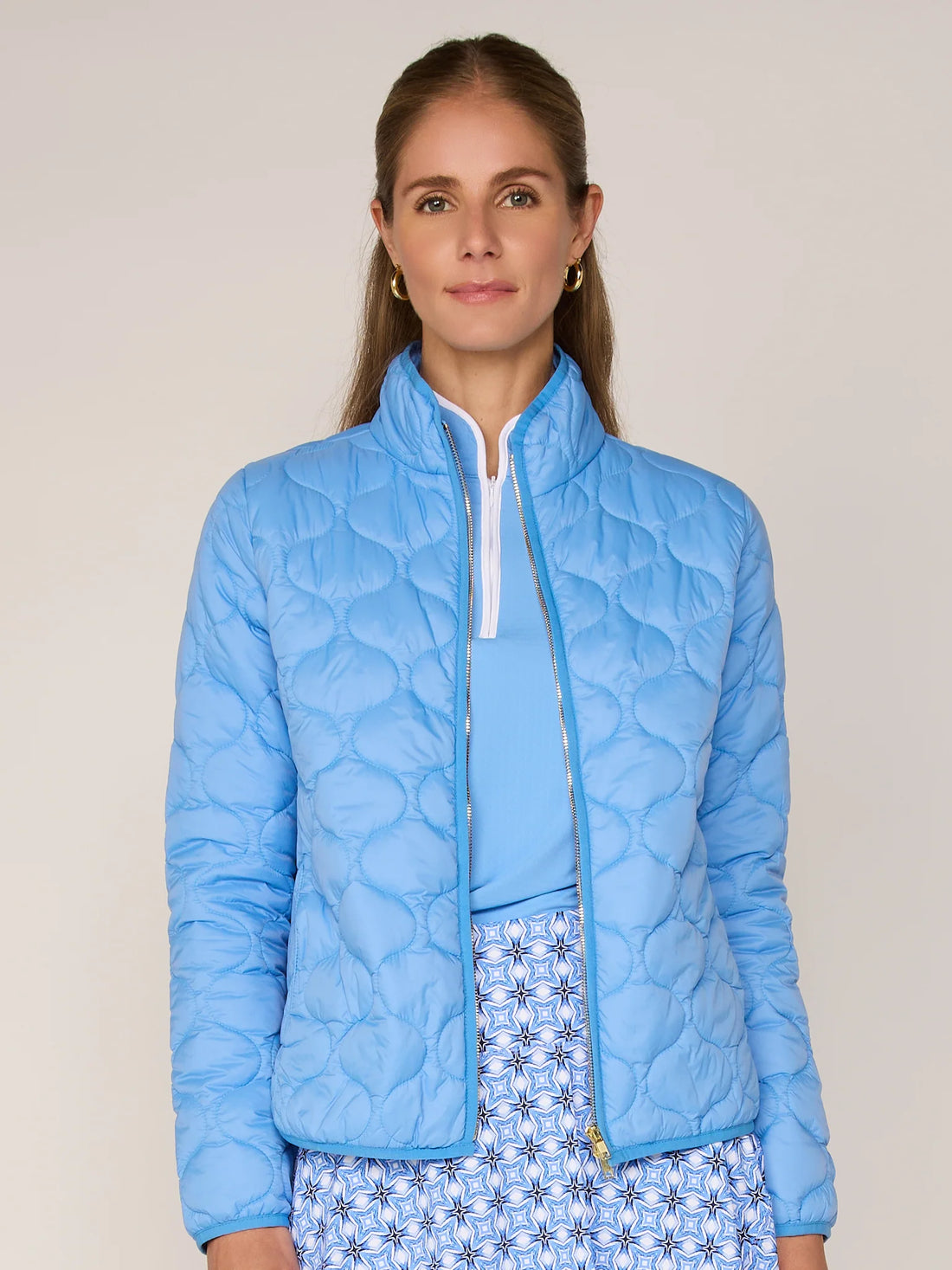 Woman wearing a light blue quilted jacket against a plain background
