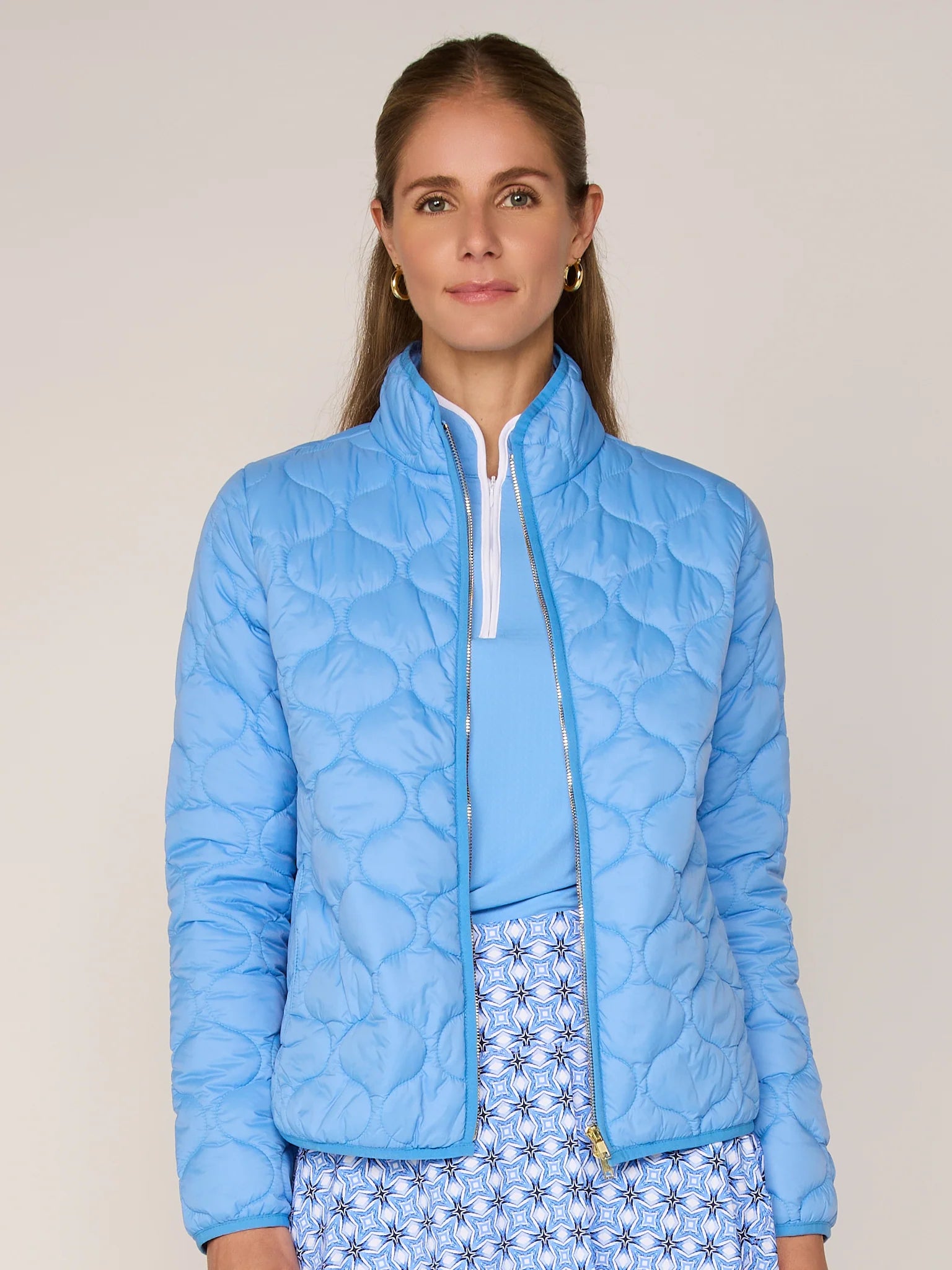 Woman wearing a light blue quilted jacket against a plain background