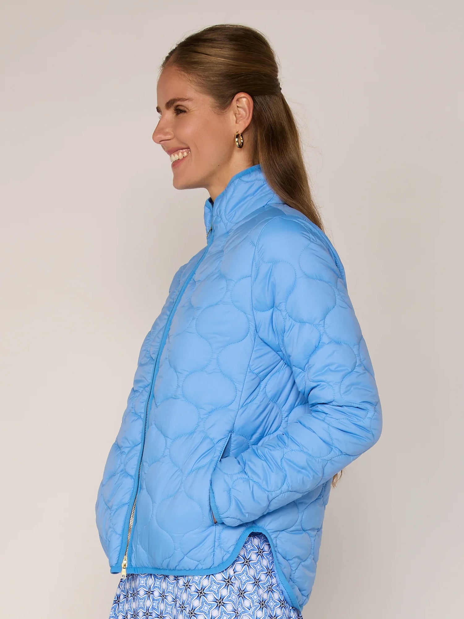 Woman wearing a blue quilted jacket against a plain background