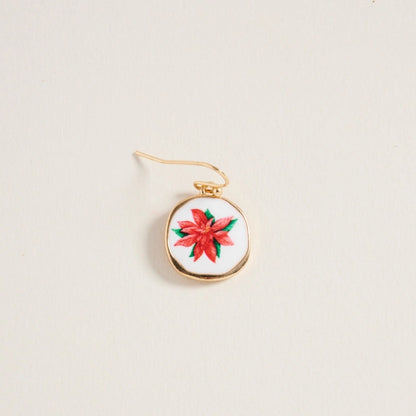 Gold pendant with a red floral design on a beige background