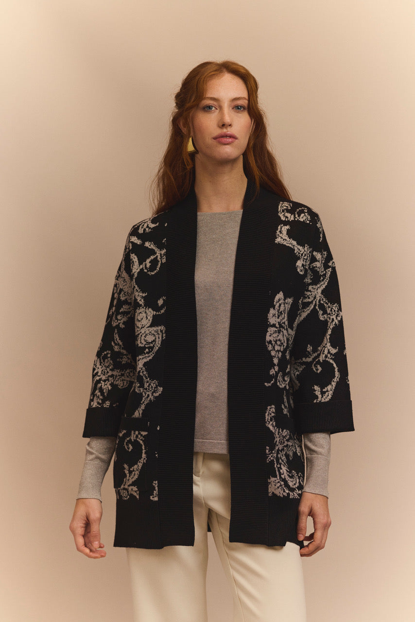 Woman wearing a black cardigan with silver embroider on a beige background