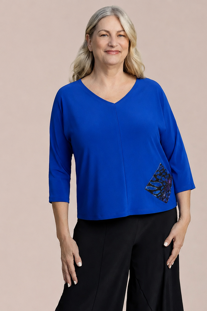 A woman modeling a bright blue V-neck top with three-quarter sleeves and a black geometric patterned accent pocket by Sympli Revel Top in Lapis