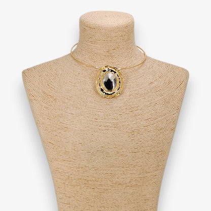 Gold necklace with a large pendant on a mannequin bust against a white background