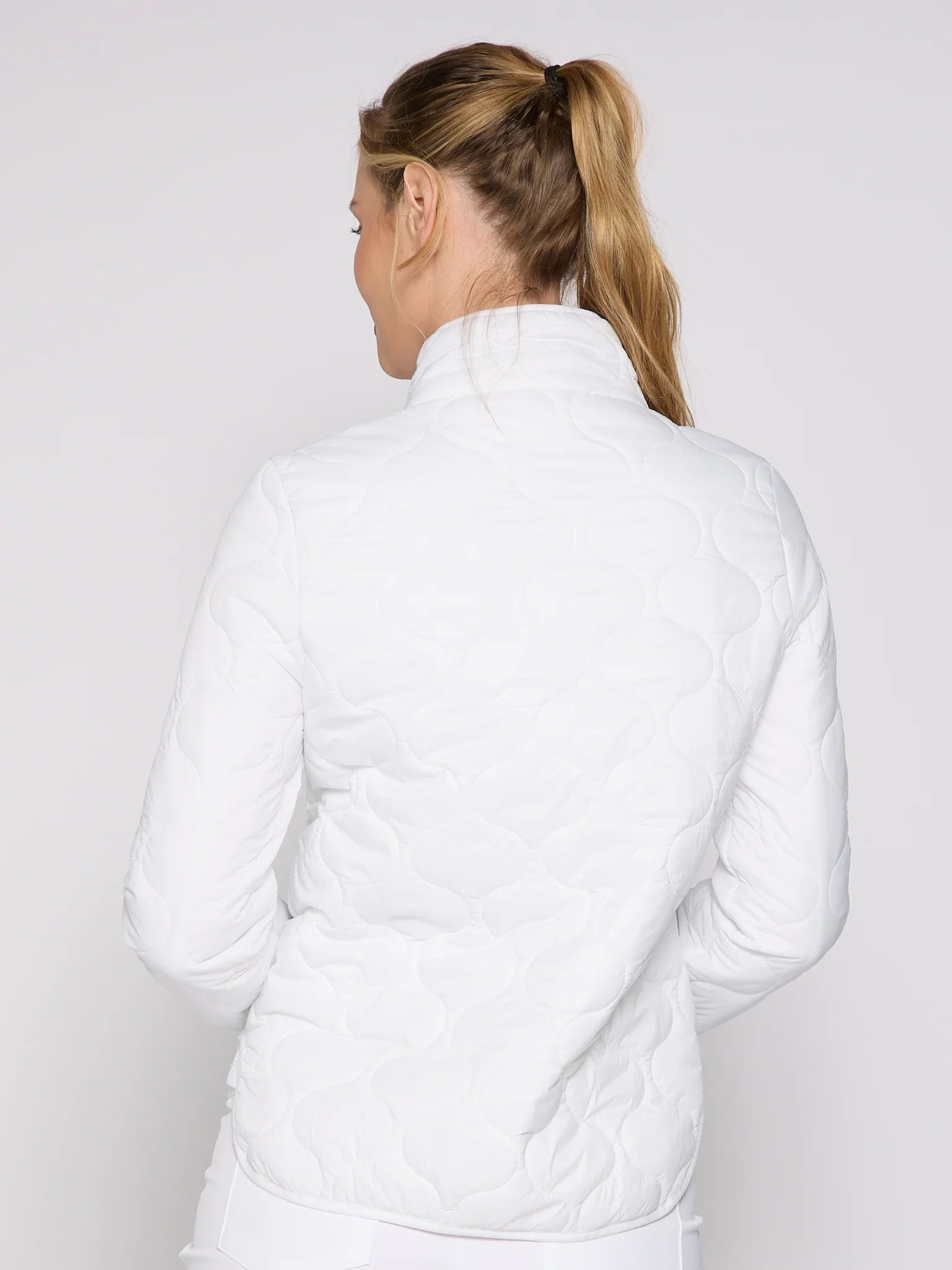 Person wearing a white quilted jacket on a plain background