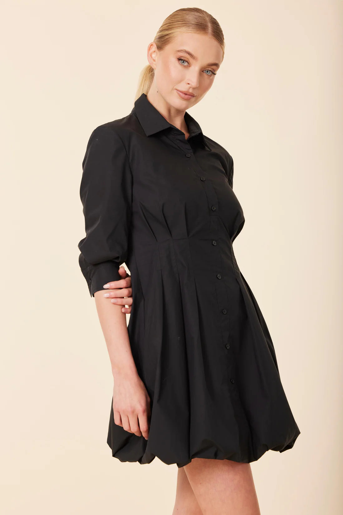 Woman wearing a black dress against a beige background