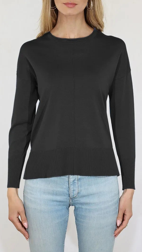 Person wearing a black long-sleeve top and light blue jeans on a white background