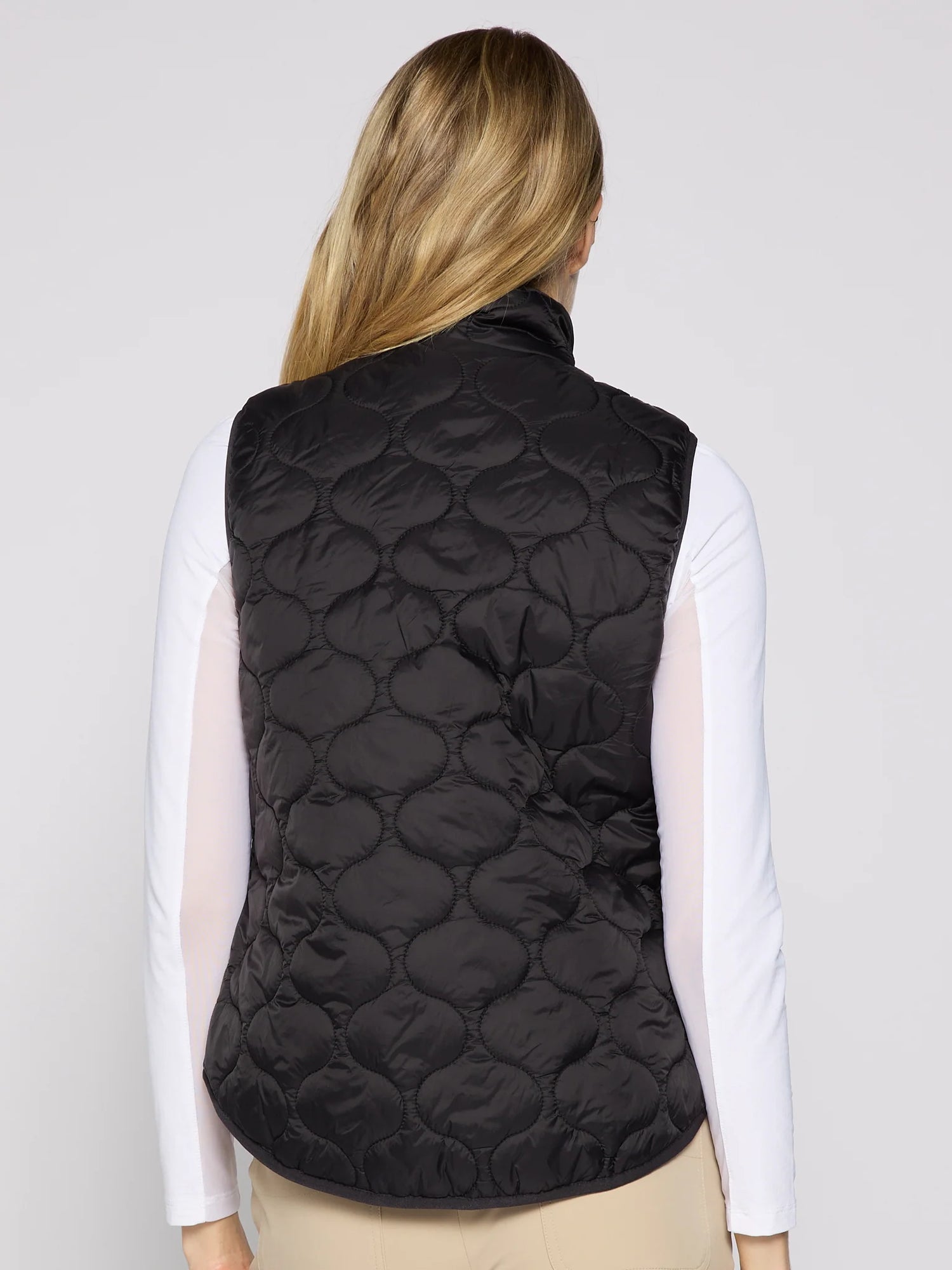 Person wearing a black quilted vest on a plain background