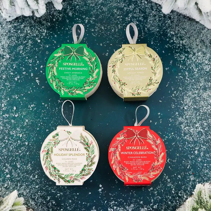 Four Spongelle bath body buffer ornaments on a textured green background with snowflake decorations.