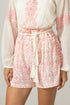 White blouse with pink floral pattern and matching shorts on a neutral background