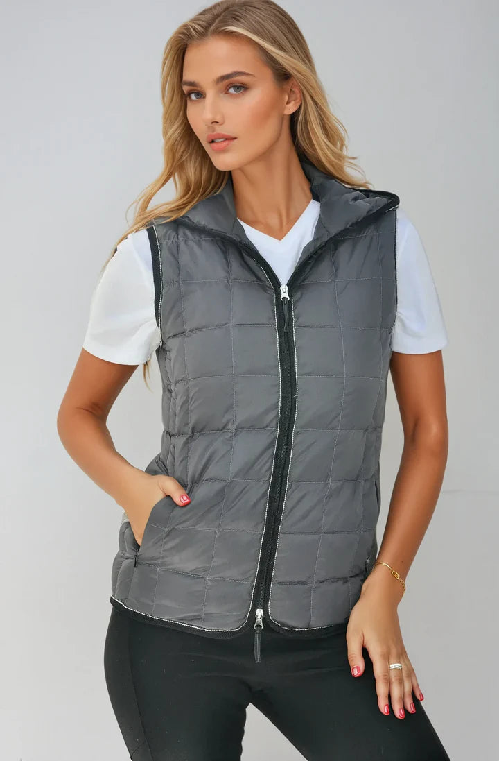 Woman wearing a gray puffer vest over a white shirt on a plain background