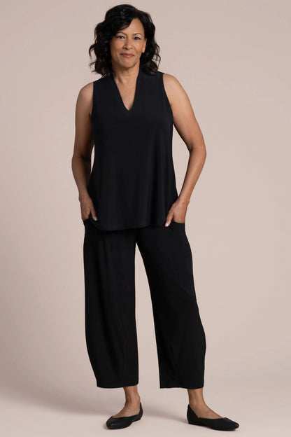 A woman wearing a sleeveless black V-neck top and black pants by Sympli Deep V Trapeze Tank
