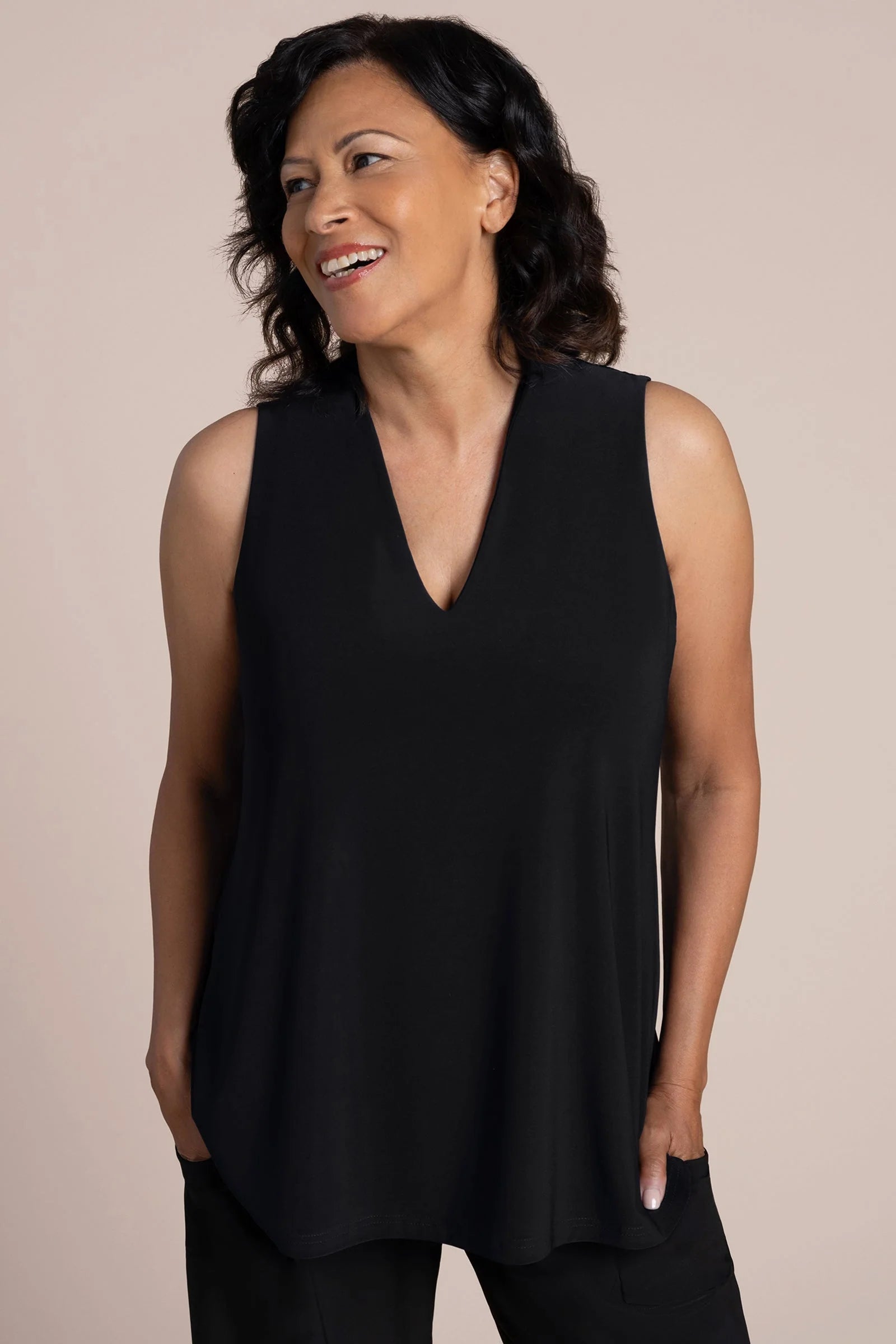 A woman wearing a sleeveless black V-neck top and black pants by Sympli Deep V Trapeze Tank