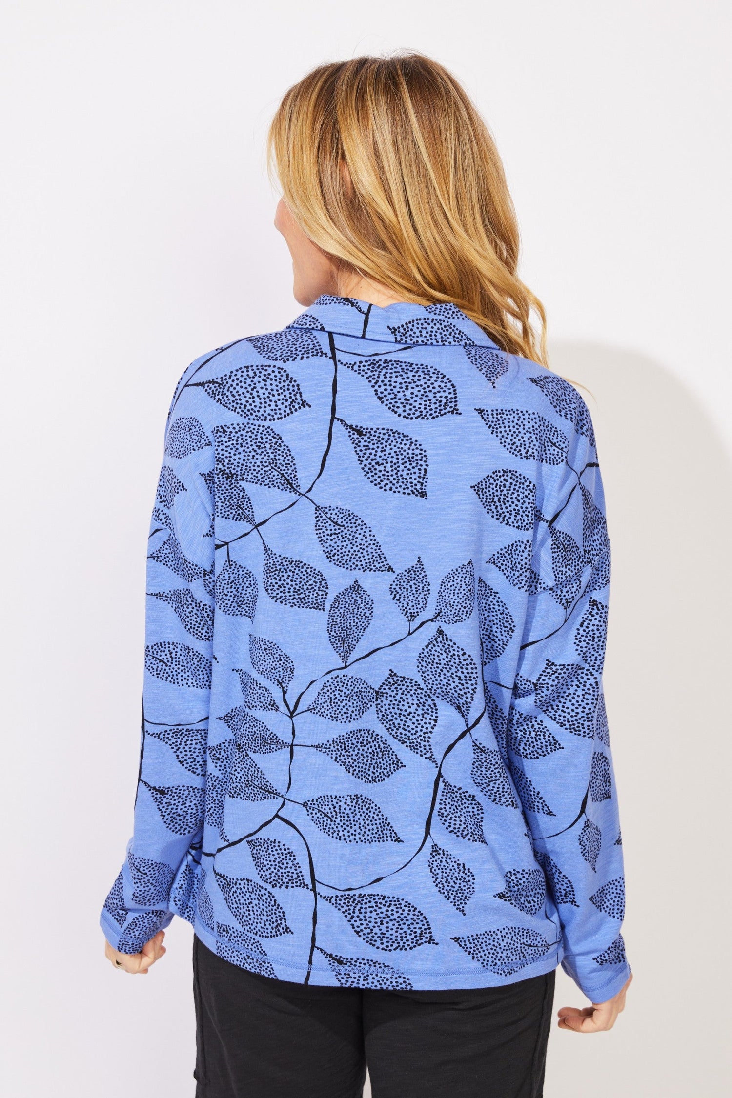 A woman wearing a light blue long-sleeve quarter-zip pullover with a dark blue leaf pattern escape by habitat E96112 BajBlue Quarter Zip