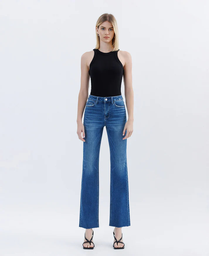 Woman wearing blue jeans and a black top on a white background