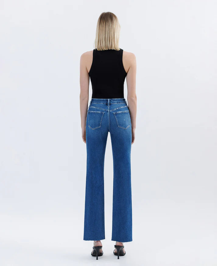 Person wearing blue jeans and a black top on a white background