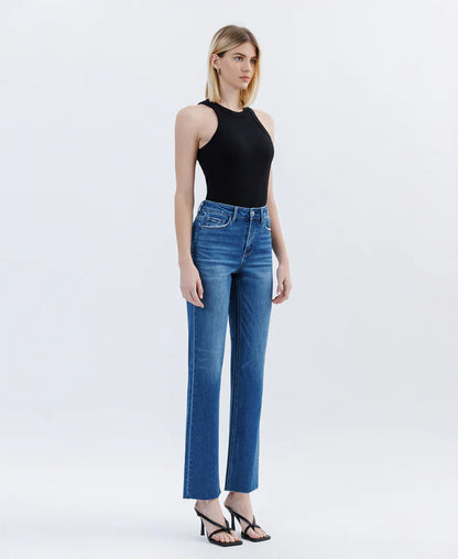 Woman wearing blue jeans and a black top on a white background