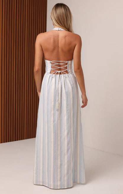 Woman wearing a white halter neck dress with blue stripes against a neutral background