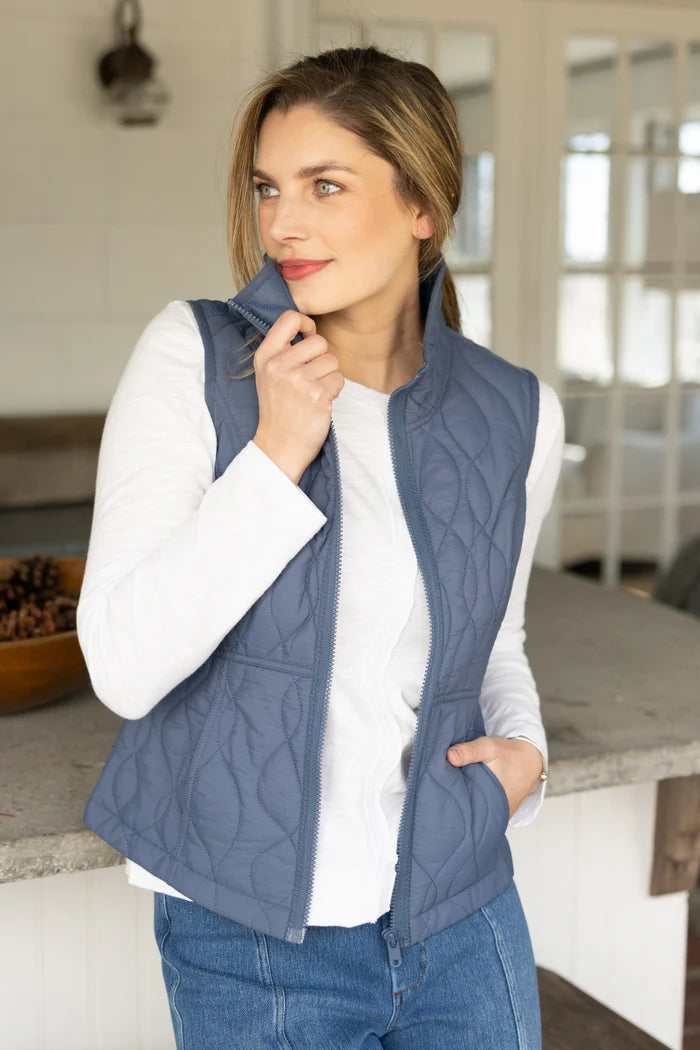 Woman wearing a blue quilted vest against a kitchen background