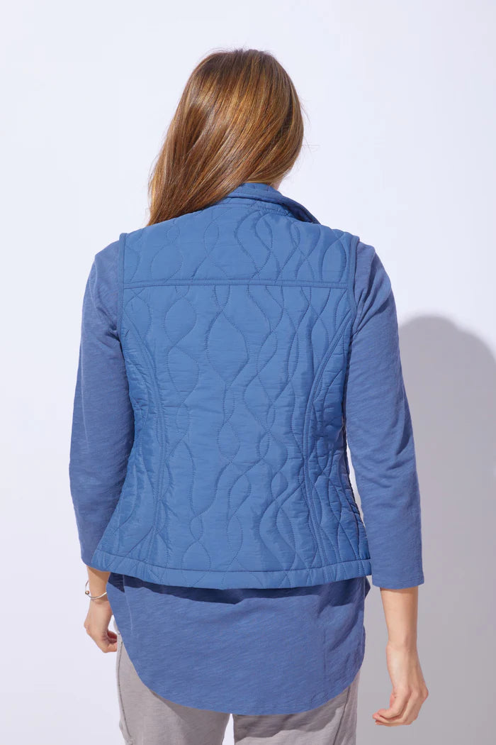 Woman wearing a blue quilted vest against a white background