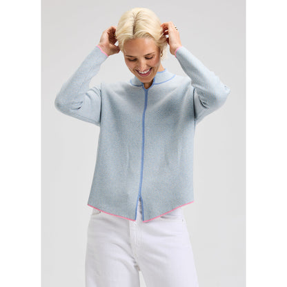 Person wearing a light blue sweater with dark blue and pink details with a plain background