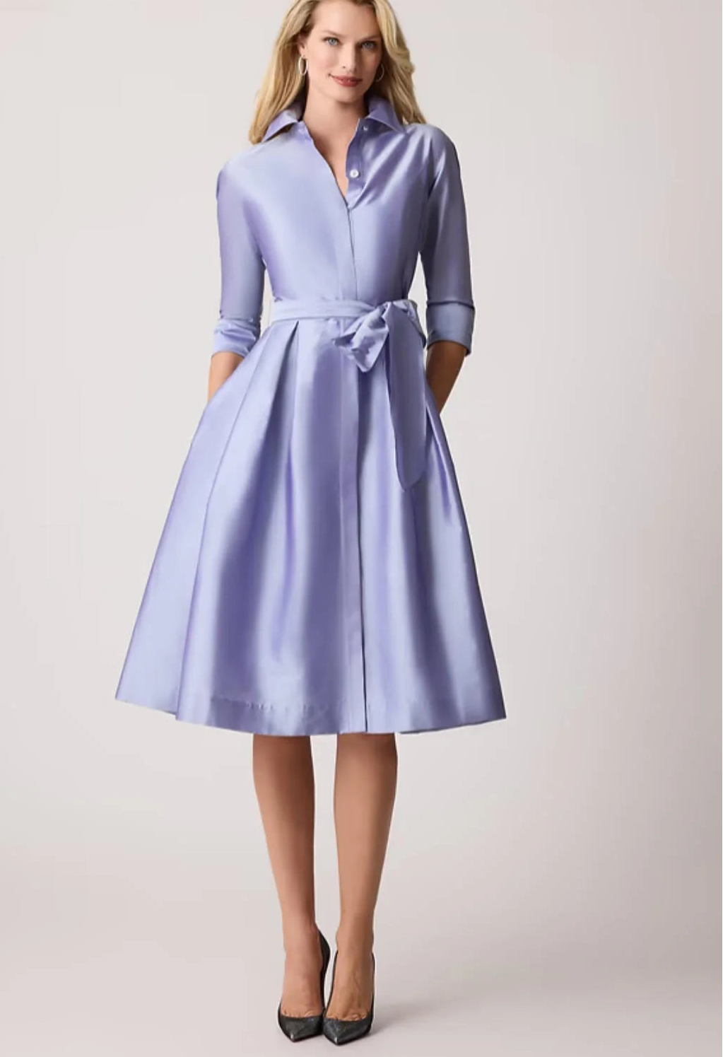 Woman wearing a light blue dress with a belt on a white background