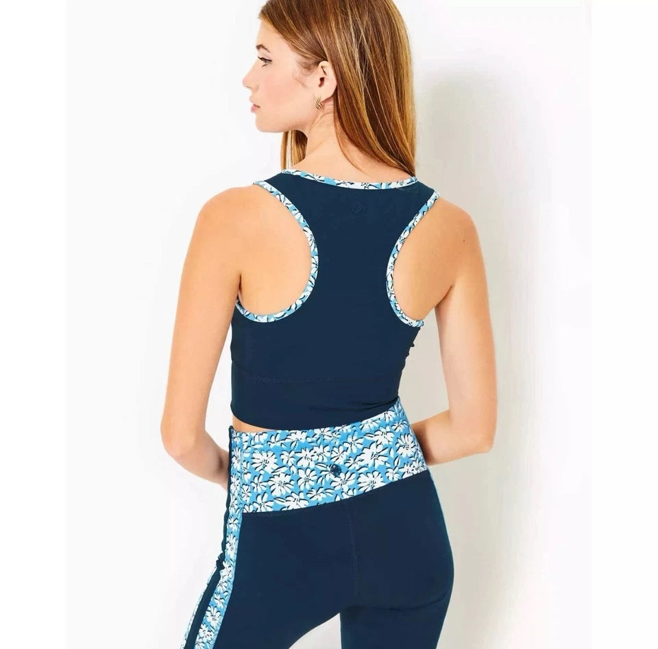 Woman wearing a navy blue sports bra and leggings with white floral patterns on a white background