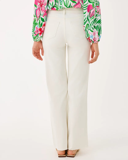 Person wearing a colorful floral blouse and white pants on a white background