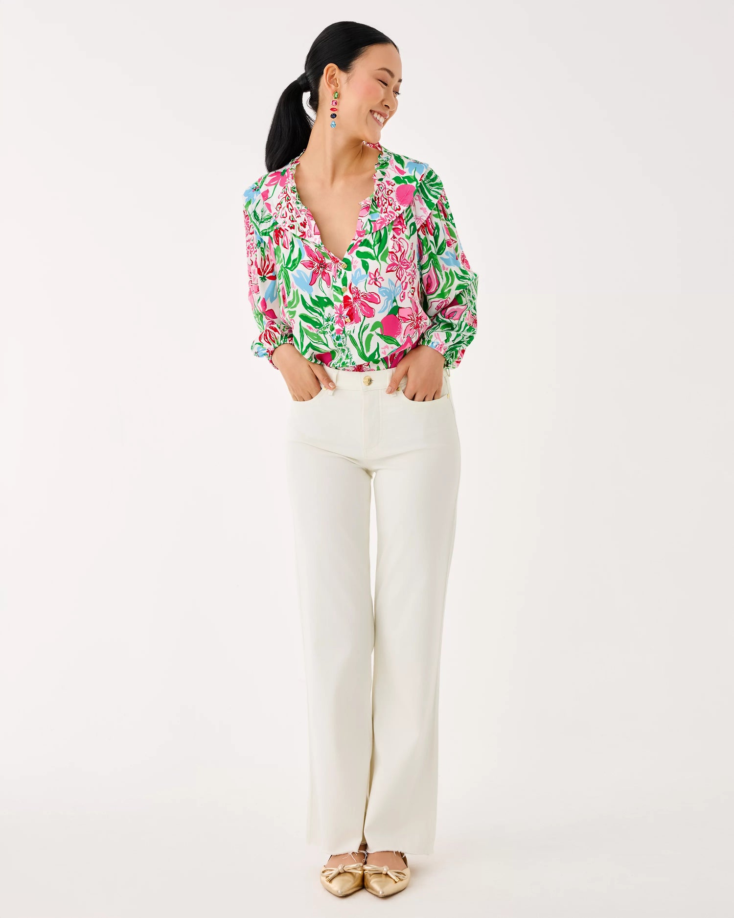 Woman wearing a floral blouse and white pants on a white background