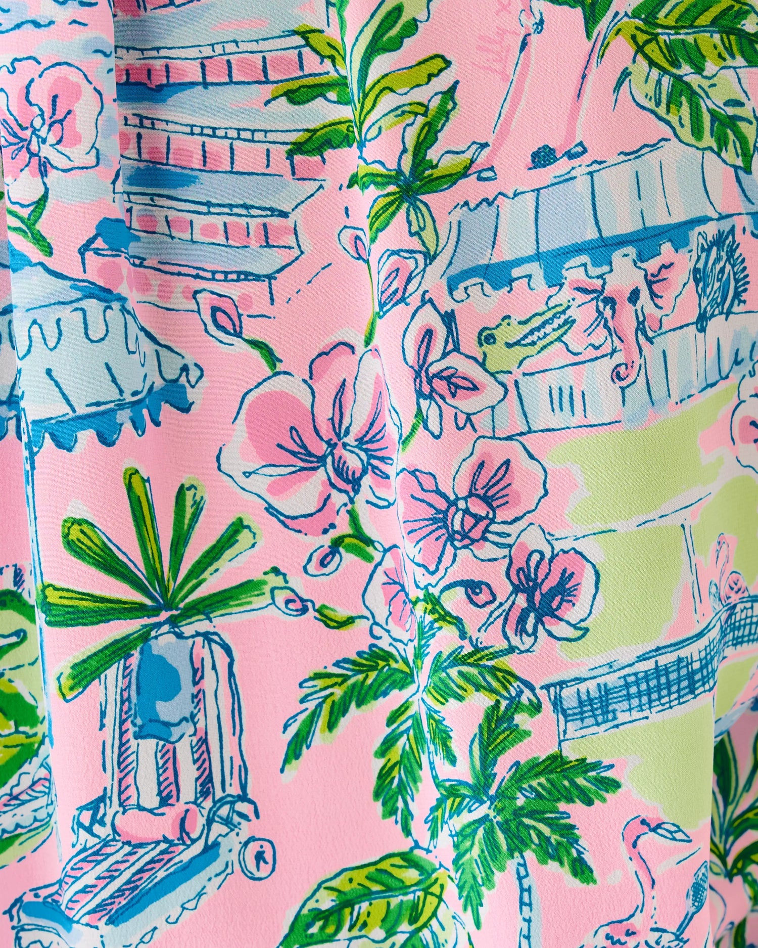Colorful fabric with tropical patterns including palm trees and buildings on a pink background.