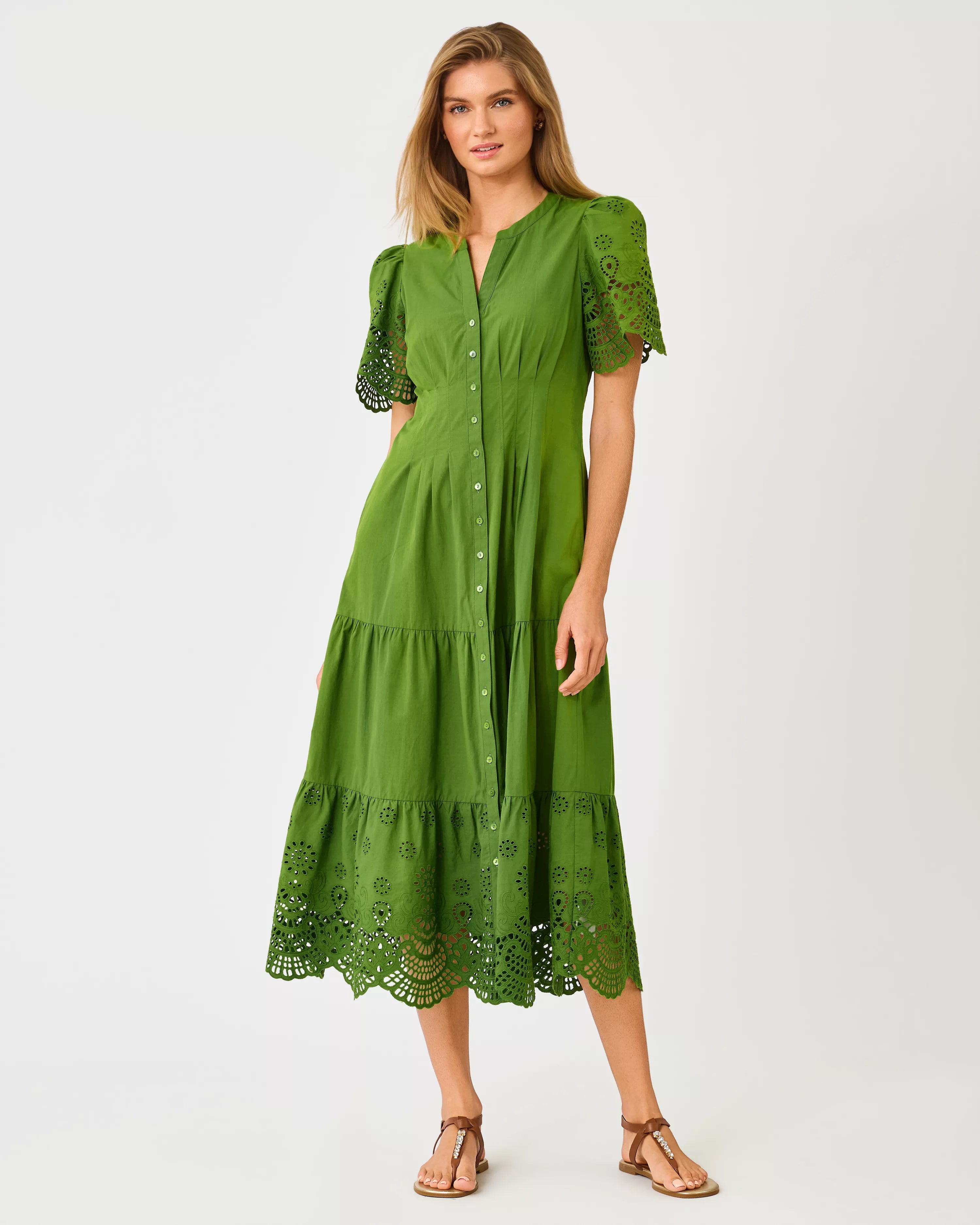 A woman modeling a green midi dress with short puff sleeves, a button-front neckline, and eyelet lace trim at the hem and sleeve cuffs lilly pulitzer wayland midi dress color Oregano Scalloped Eyelet Border Poplin