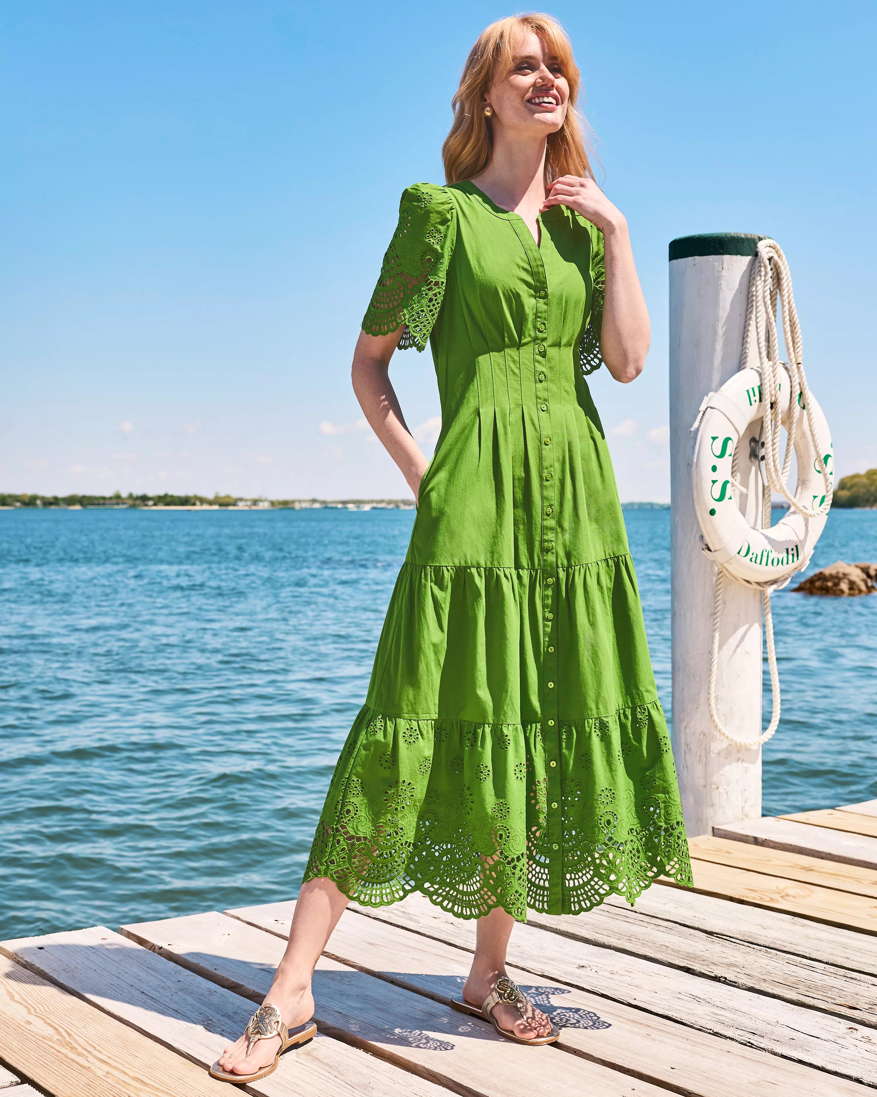 A woman modeling a green midi dress with short puff sleeves, a button-front neckline, and eyelet lace trim at the hem and sleeve cuffs lilly pulitzer wayland midi dress color Oregano Scalloped Eyelet Border Poplin