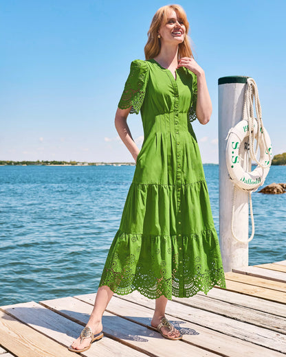 A woman modeling a green midi dress with short puff sleeves, a button-front neckline, and eyelet lace trim at the hem and sleeve cuffs lilly pulitzer wayland midi dress color Oregano Scalloped Eyelet Border Poplin