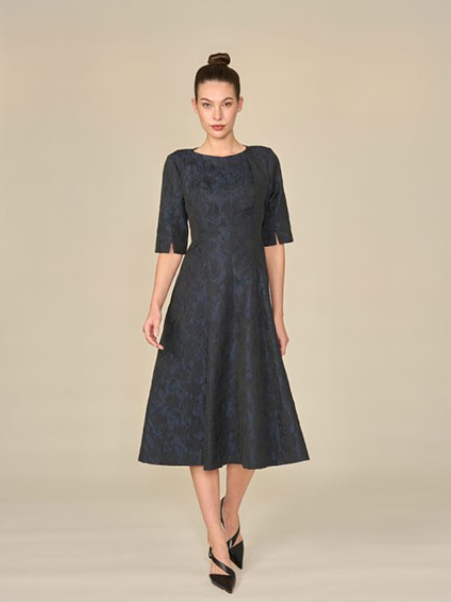 Woman wearing a dark blue patterned dress against a beige background